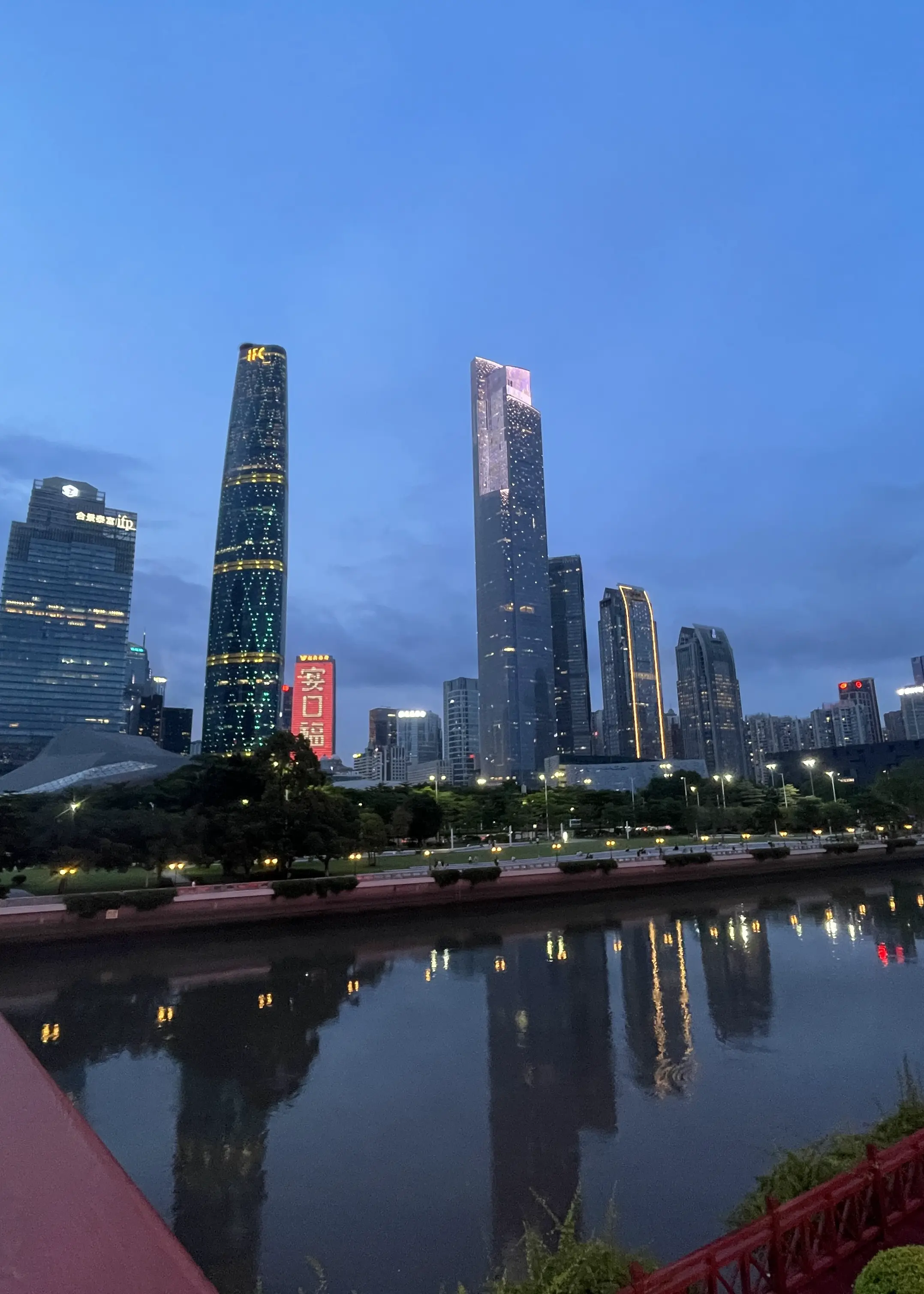 傍晚广州的高楼与水面倒影,前景可见栏杆